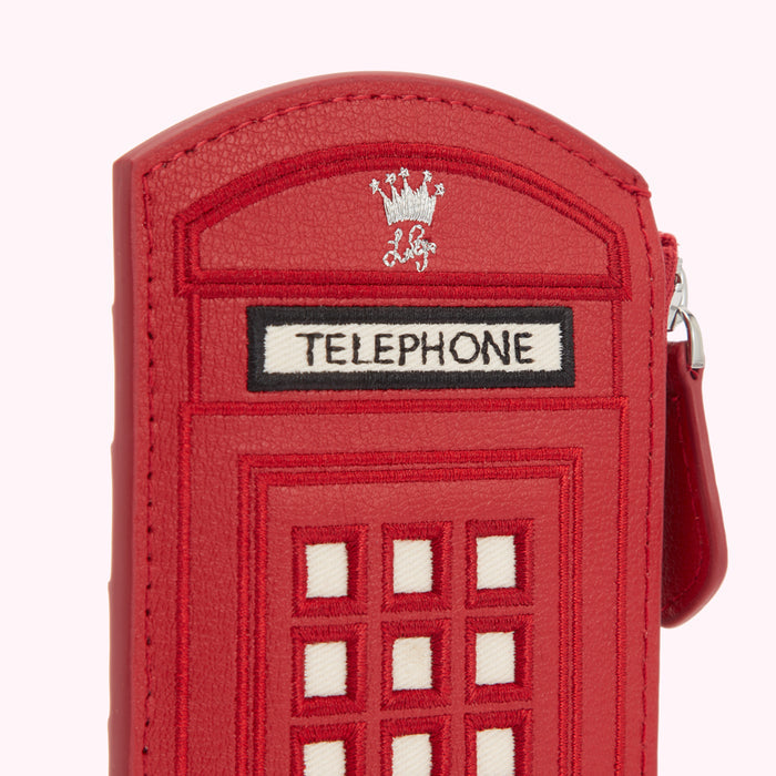 Close-up of a red leather purse shaped like a British telephone booth, with embroidered details and a small crown emblem.