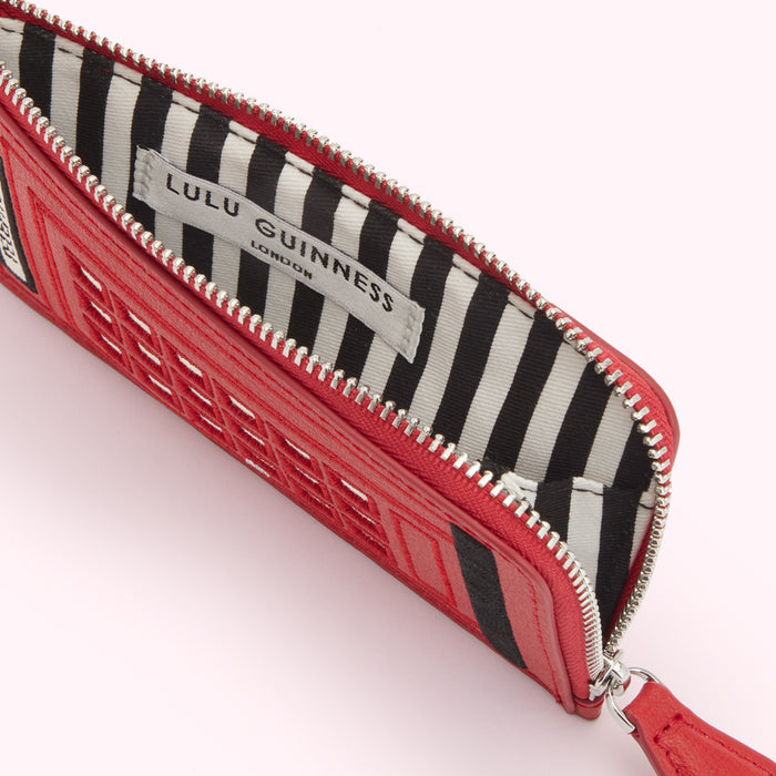 Red Lulu Guinness London phone box-shaped zip pouch open to reveal black and white striped interior.