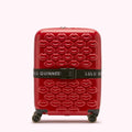 Red Lulu Guinness suitcase with a lip print and a black luggage strap.