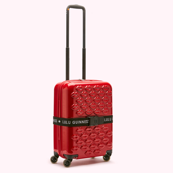 Red Lulu Guinness carry-on suitcase with a lip pattern.