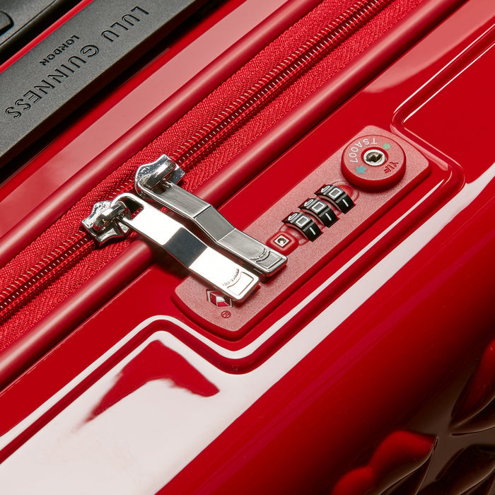 Close-up of a red and white luggage's TSA-approved combination lock and zipper.