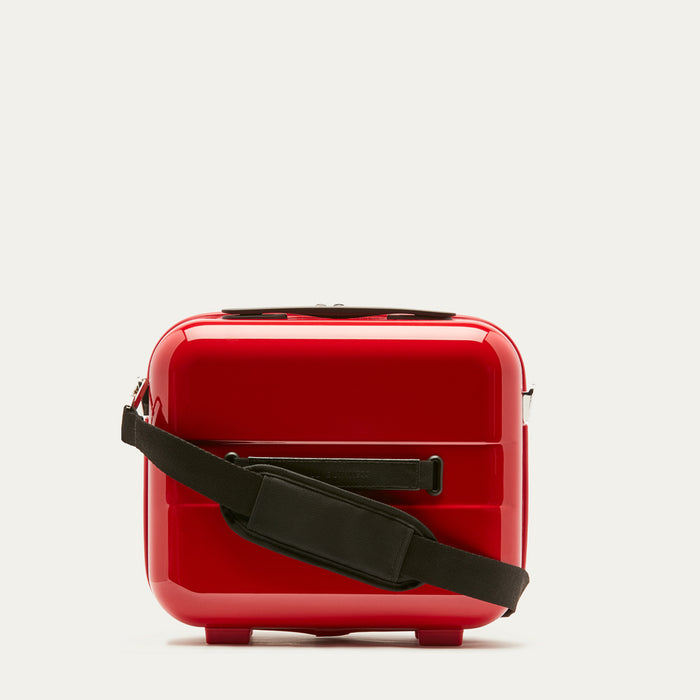 Red vanity case with a black strap on a light gray background