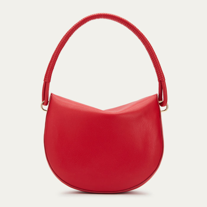 Red leather handbag with a curved shape and braided top handle on a beige background.