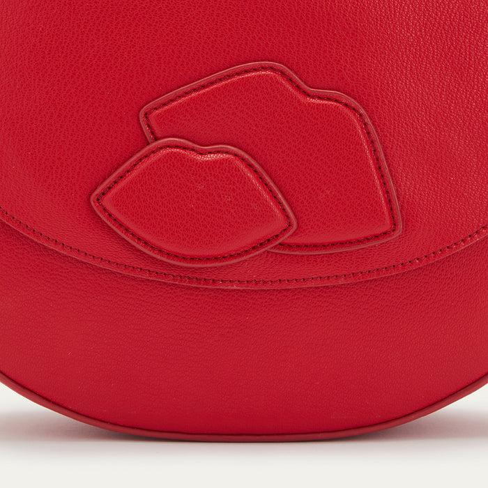 Close-up of a red Lulu Guinness handbag with a lip design and gold logo.