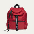 Red backpack with black straps and 'Lulu Guinness' branding on a white background