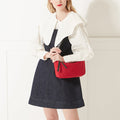 Model in a white shirt, denim dress and red lipstick wearing a red nylon shoulder bag with branded 'Lulu Guinness' shoulder strap.