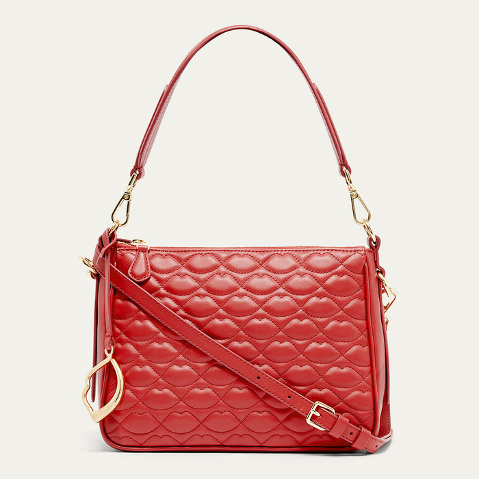 Red quilted handbag with gold accents on a light beige background