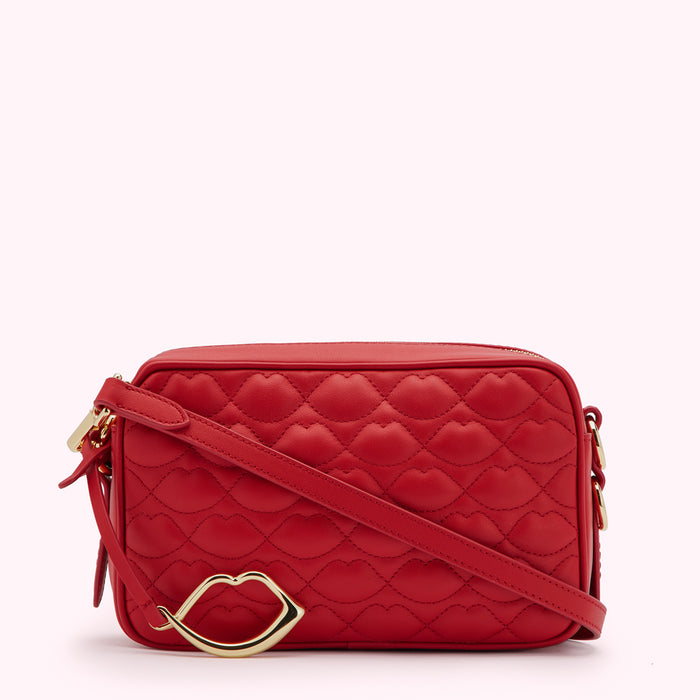 Red quilted crossbody bag with gold lip charm.