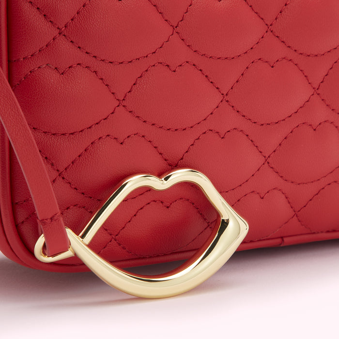 Close-up of a red quilted handbag with a gold lip-shaped clasp.