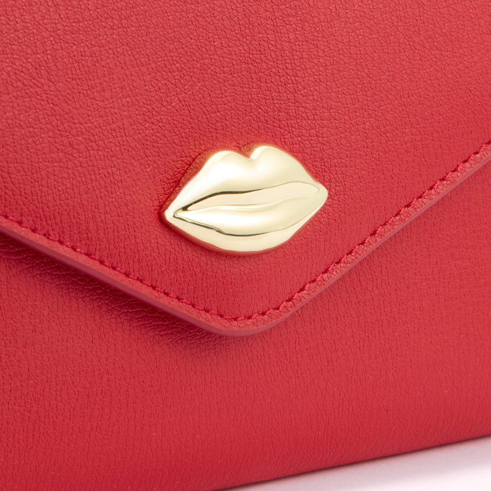 Close-up of a red leather wallet with a gold lip-shaped accent.