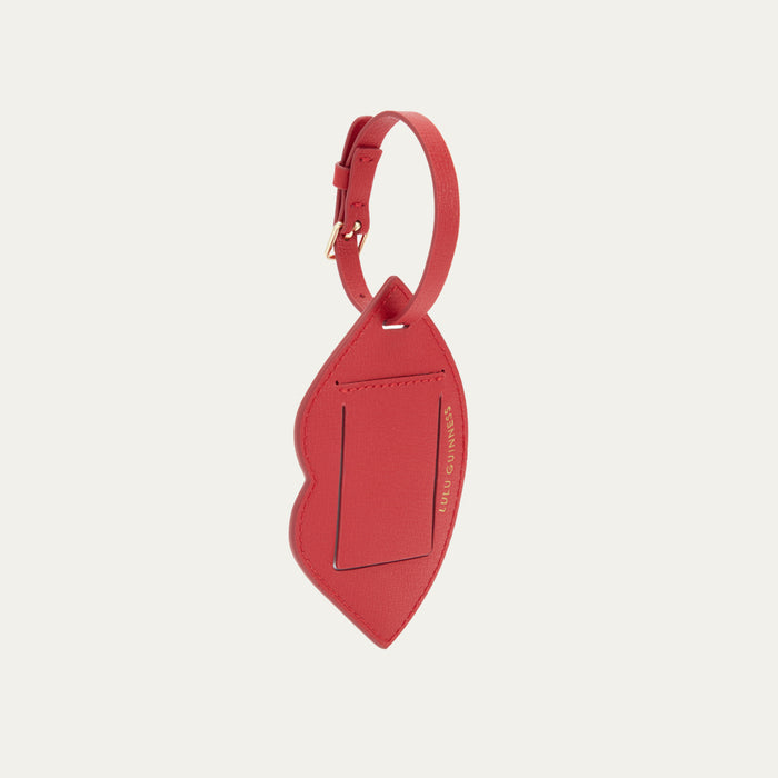A back image of a red leather luggage tag with buckle fastening and a foil print 'Lulu Guinness' logo.