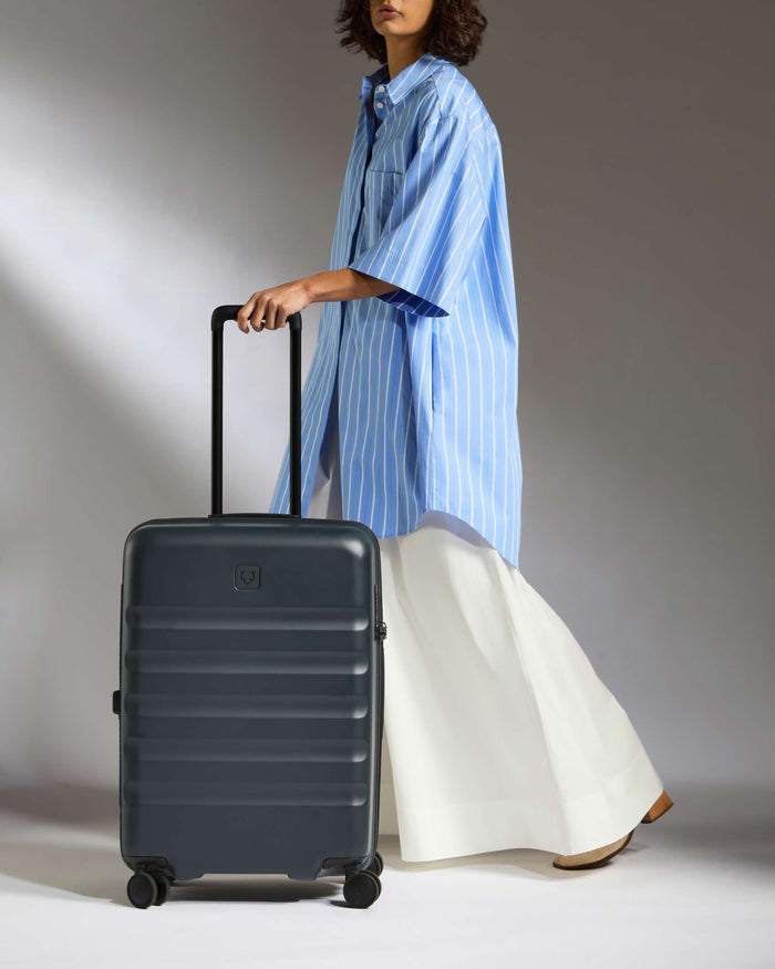 a woman in a blue shirt and white skirt holding a suitcase