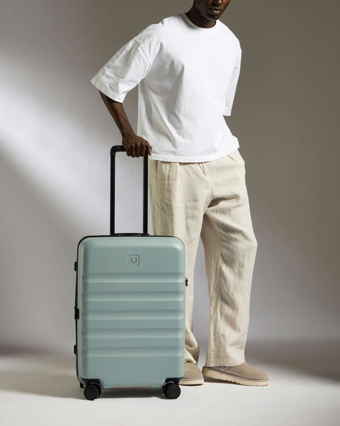 a man in a white shirt and khaki pants holding a suitcase