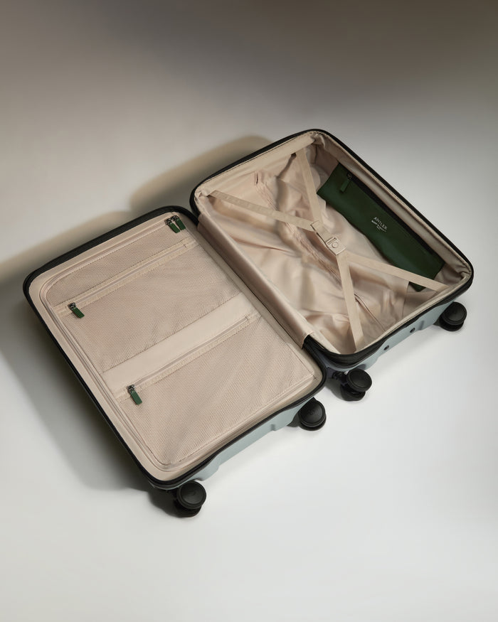 a suitcase with wheels and a green purse inside
