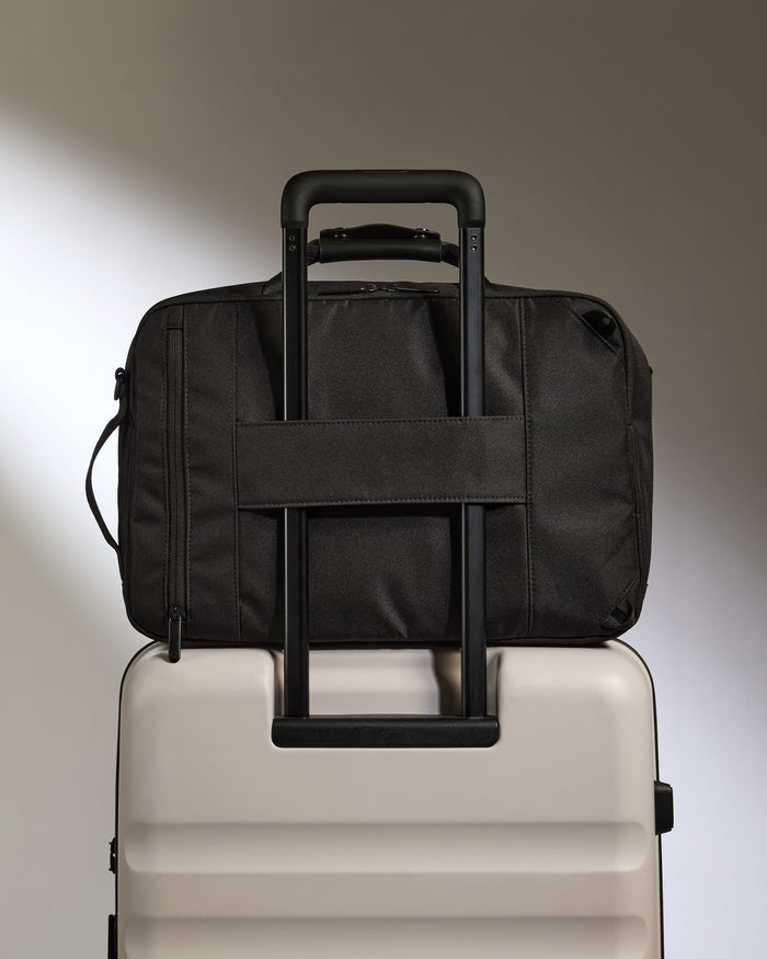 a black bag on top of a white suitcase