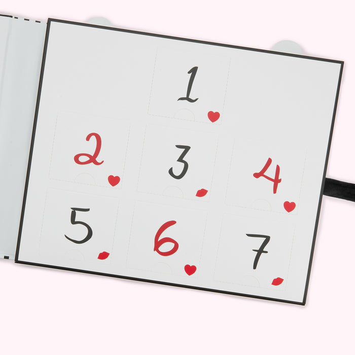 Open black photo album with numbered pages and small red hearts and lips.