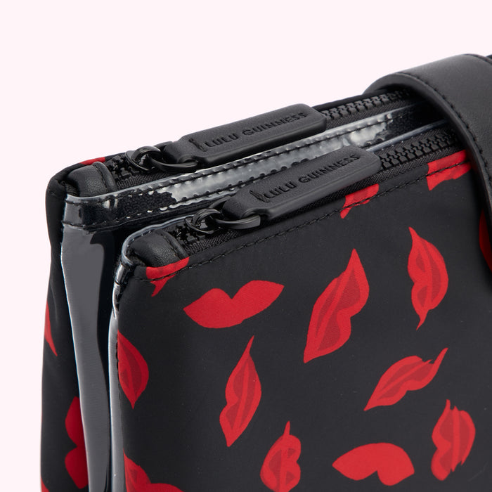 Close-up of a black Lulu Guinness makeup bag with a red lips print and double zippers.