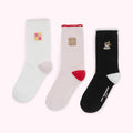 Three pairs of Lulu Guinness socks with embroidered images of a pink and yellow biscuit, a brown biscuit, and a cup and saucer.