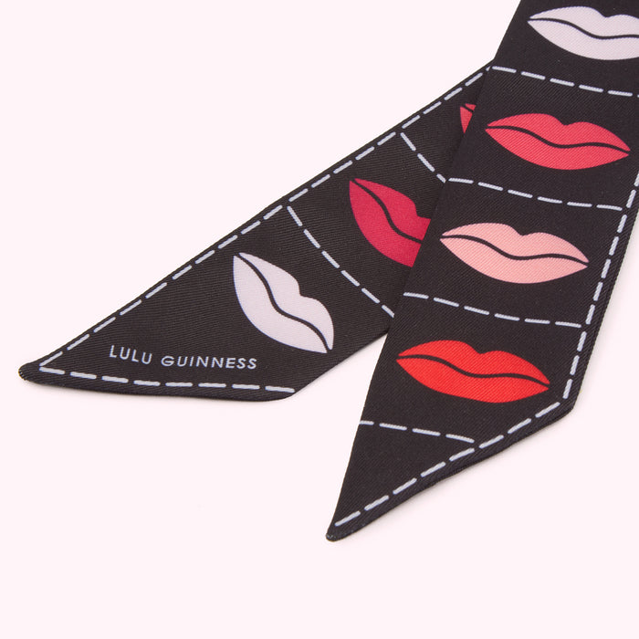 Close-up of a black Lulu Guinness scarf with a repeated pattern of lips in various colours.
