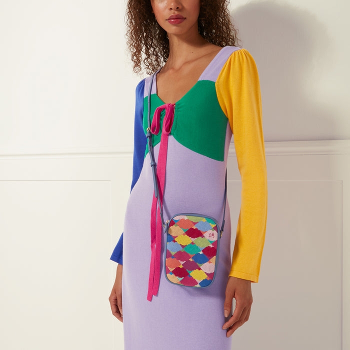 Woman wearing a colourful knit dress and a small, multi-coloured crossbody bag.