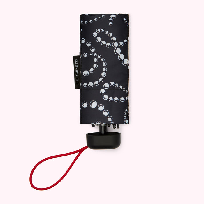 Black Lulu Guinness compact umbrella with white pearl pattern, red cord handle.