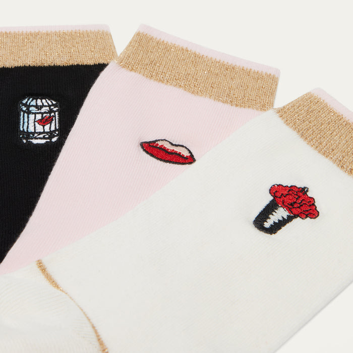Three pairs of socks with embroidered designs on a white background