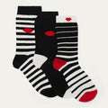Three pairs of black, white, and red striped socks with lip designs on a light gray background.