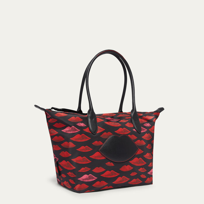 Tote bag with red lip pattern and black leather lip on the front on a light gray background