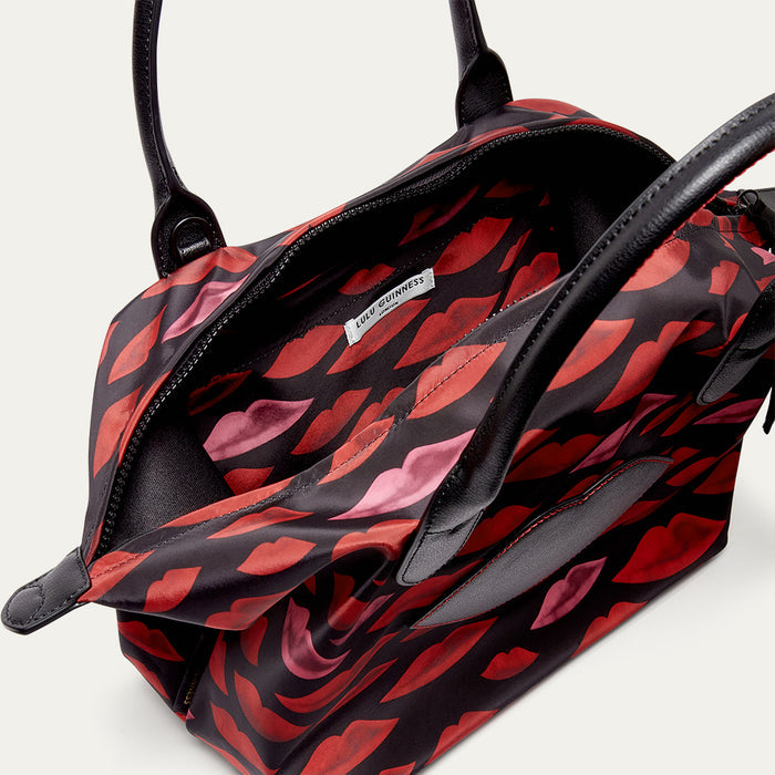 Tote bag with red lip pattern open revealing the inside on a light gray background
