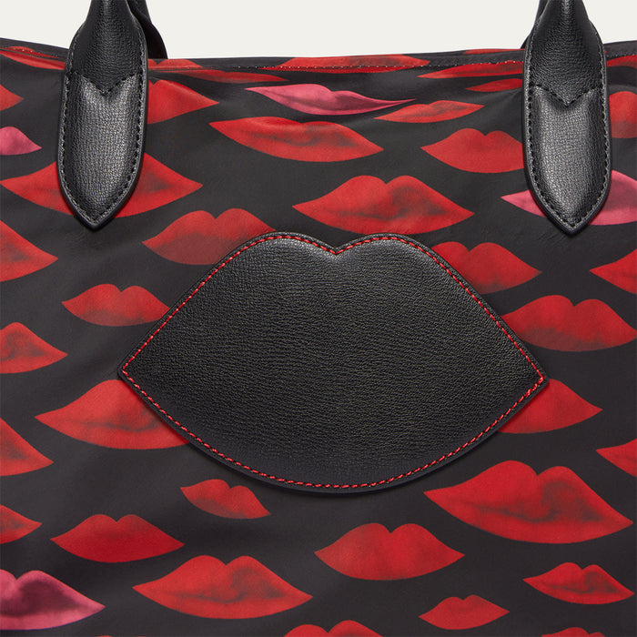 Close up image of a top bag with red and black lip print and a leather lip on the front