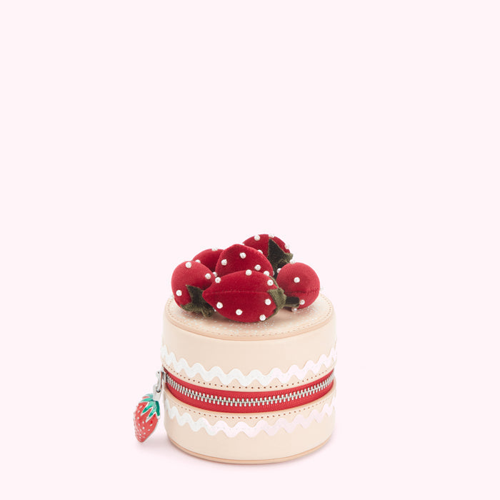 A small, beige cylindrical case decorated to look like a strawberry shortcake. The case has a red zipper and small fabric strawberries on top. The background is white.