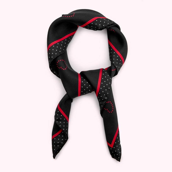 Black silk scarf with red and grey polka dots and stripes, tied in a knot.