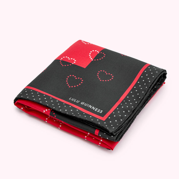 Folded Lulu Guinness scarf with a black and red pattern of hearts and polka dots.