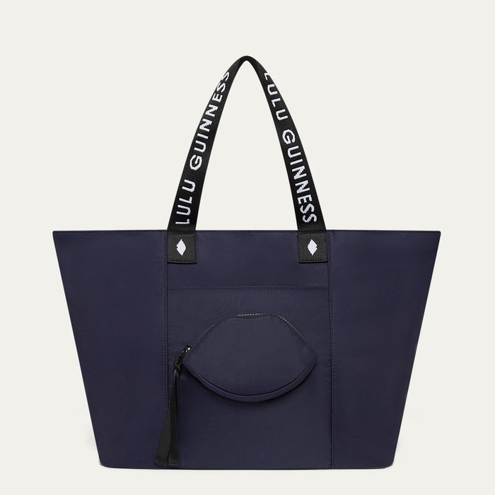 Navy tote bag with black handles featuring 'Lulu Guinness' on a light grey background