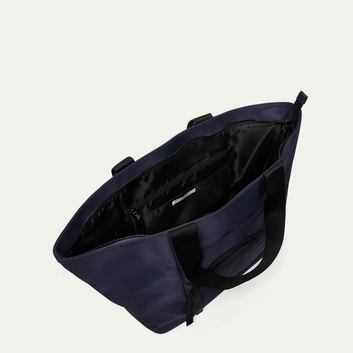 Navy blue bag with open revealing the lining on a light grey background