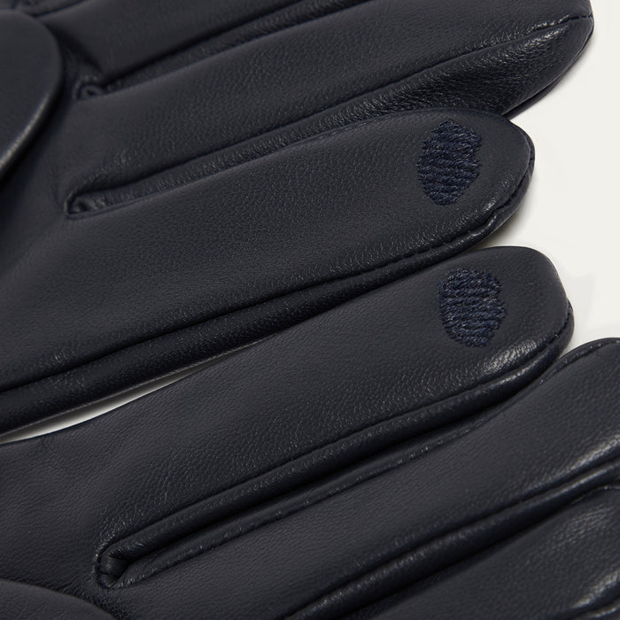 Close-up of navy leather gloves with brand logo on a white background