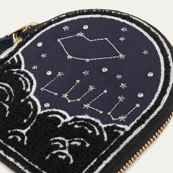 Navy blue coin purse with celestial design and 'Lulu Guinness' branding, featuring stars and constellations.