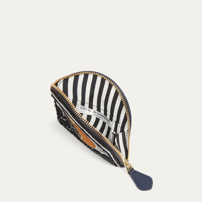 Navy coin purse open to reveal a black and white striped lining with gold zipper on a white background