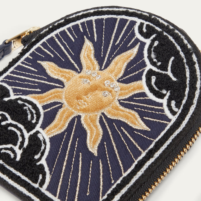 Embroidered coin purse with sun design on a dark blue background