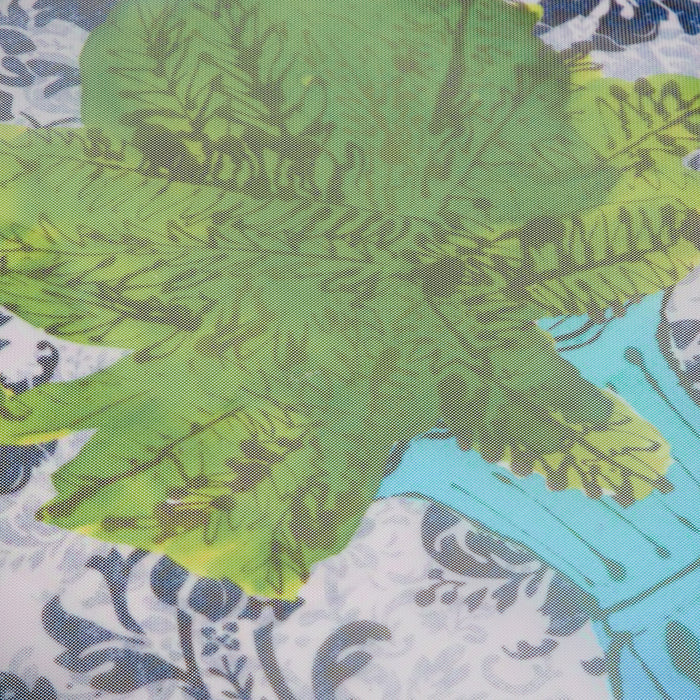Close-up of sheer fabric with a green leafy print overlaid on a white background with a damask pattern.
