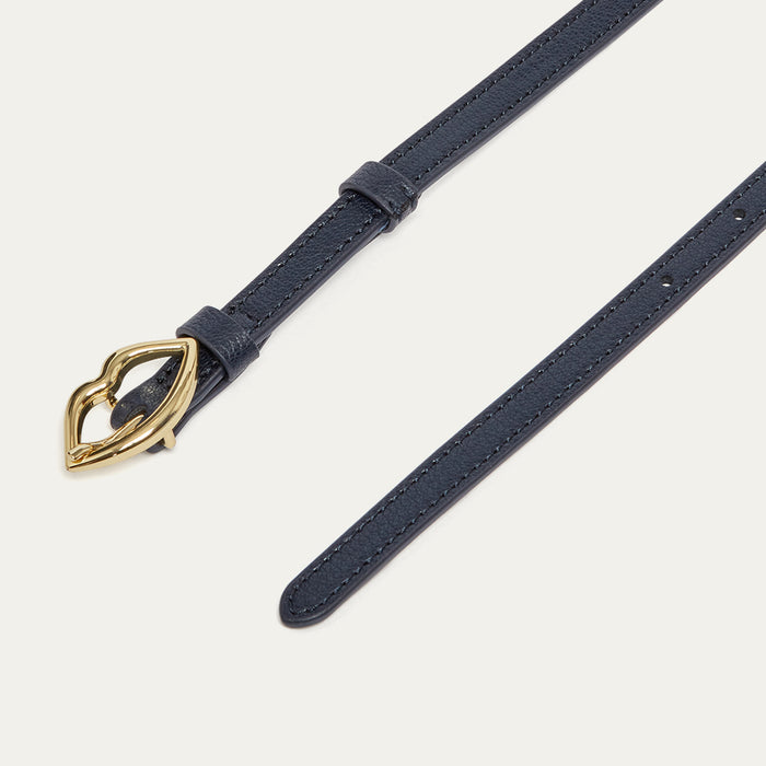 Navy leather belt with a gold lip-shaped buckle on a light grey background
