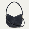 Navy leather handbag with a corded handle, crossbody strap with gold buckle and lip details on a light grey background