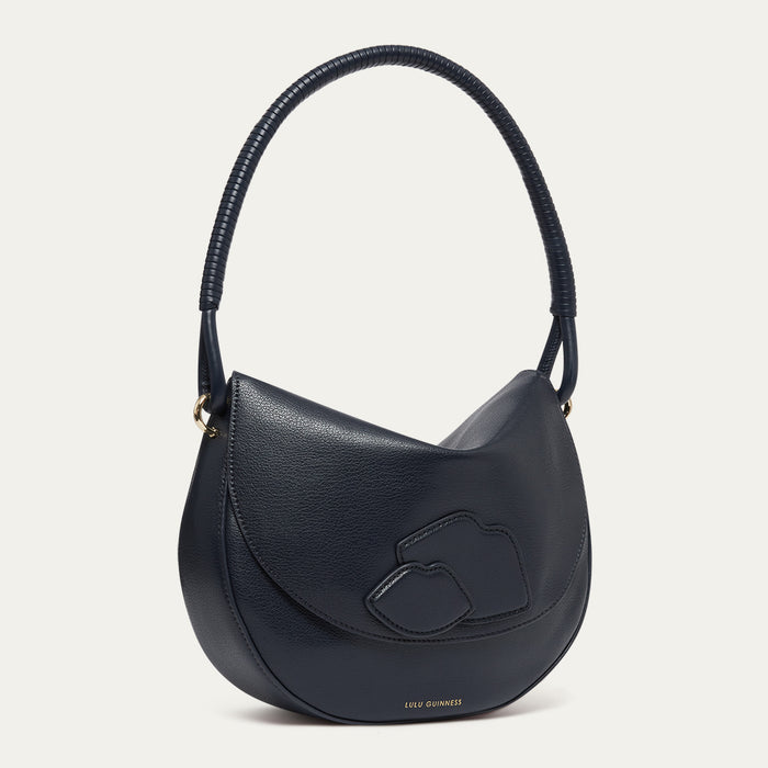 Navy blue leather shoulder bag with lip details and a corded handle on a light grey background