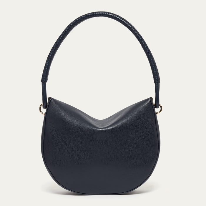 Back image of a navy blue leather shoulder bag with a corded handle on a light grey background