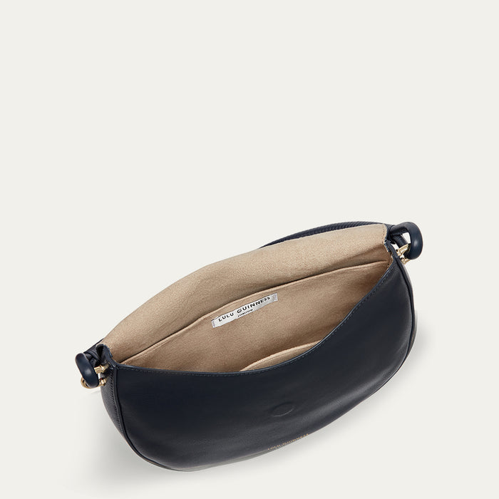 Inside image of a navy leather handbag with beige interior on a light grey background