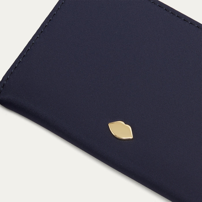 Navy blue wallet with a gold lip pin on a light grey background