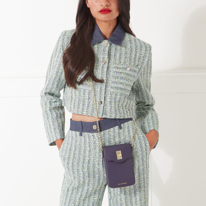 Woman in a tweed suit and a dark purple crossbody bag.