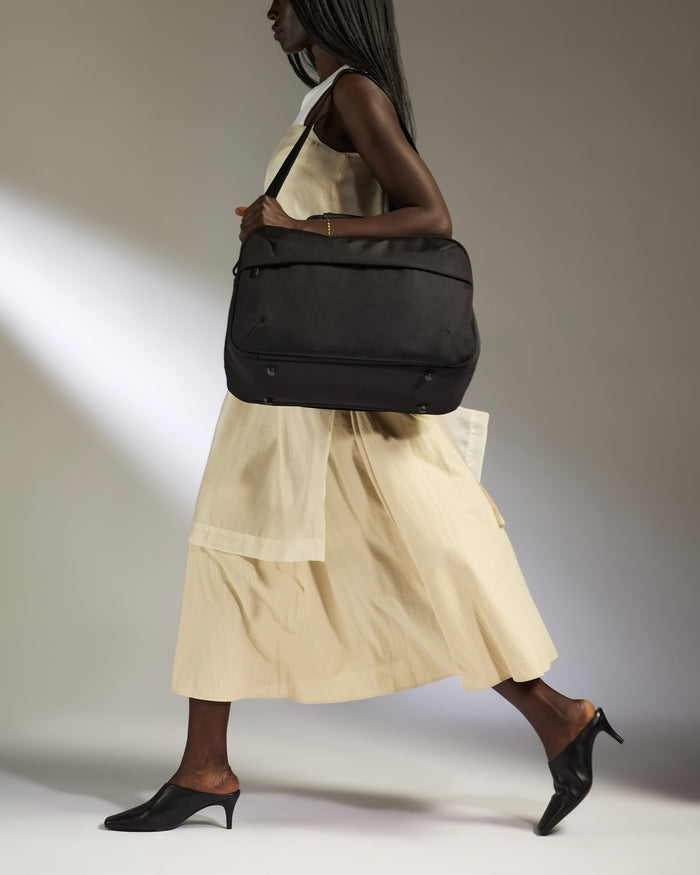 a woman in a dress carrying a bag