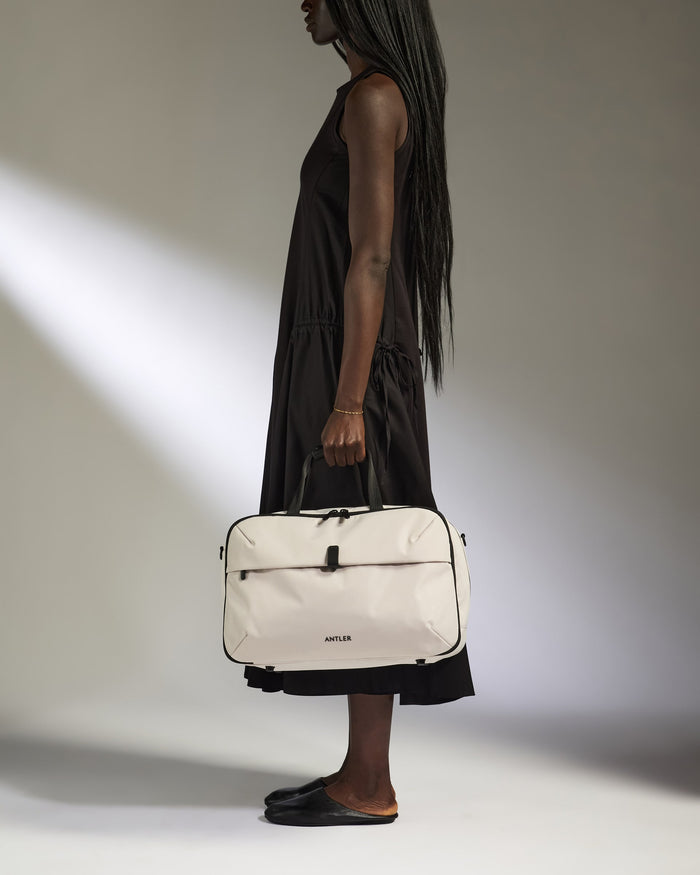 a woman in a black dress holding a white bag