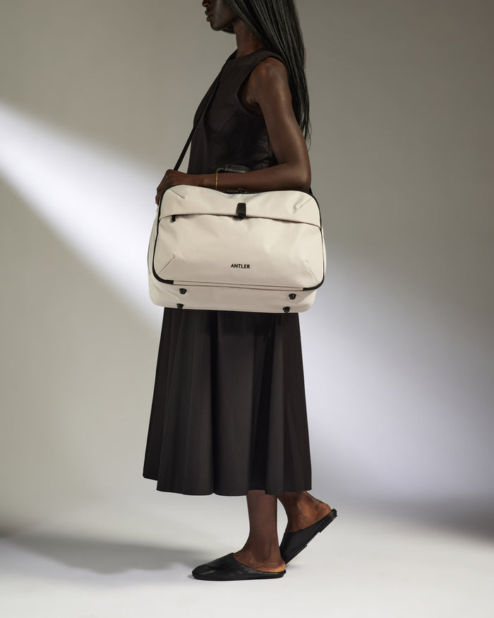 a woman in a black dress and black shoes holding a white bag